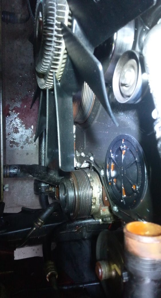 Close-up of belts and pulleys inside an engine bay during repair