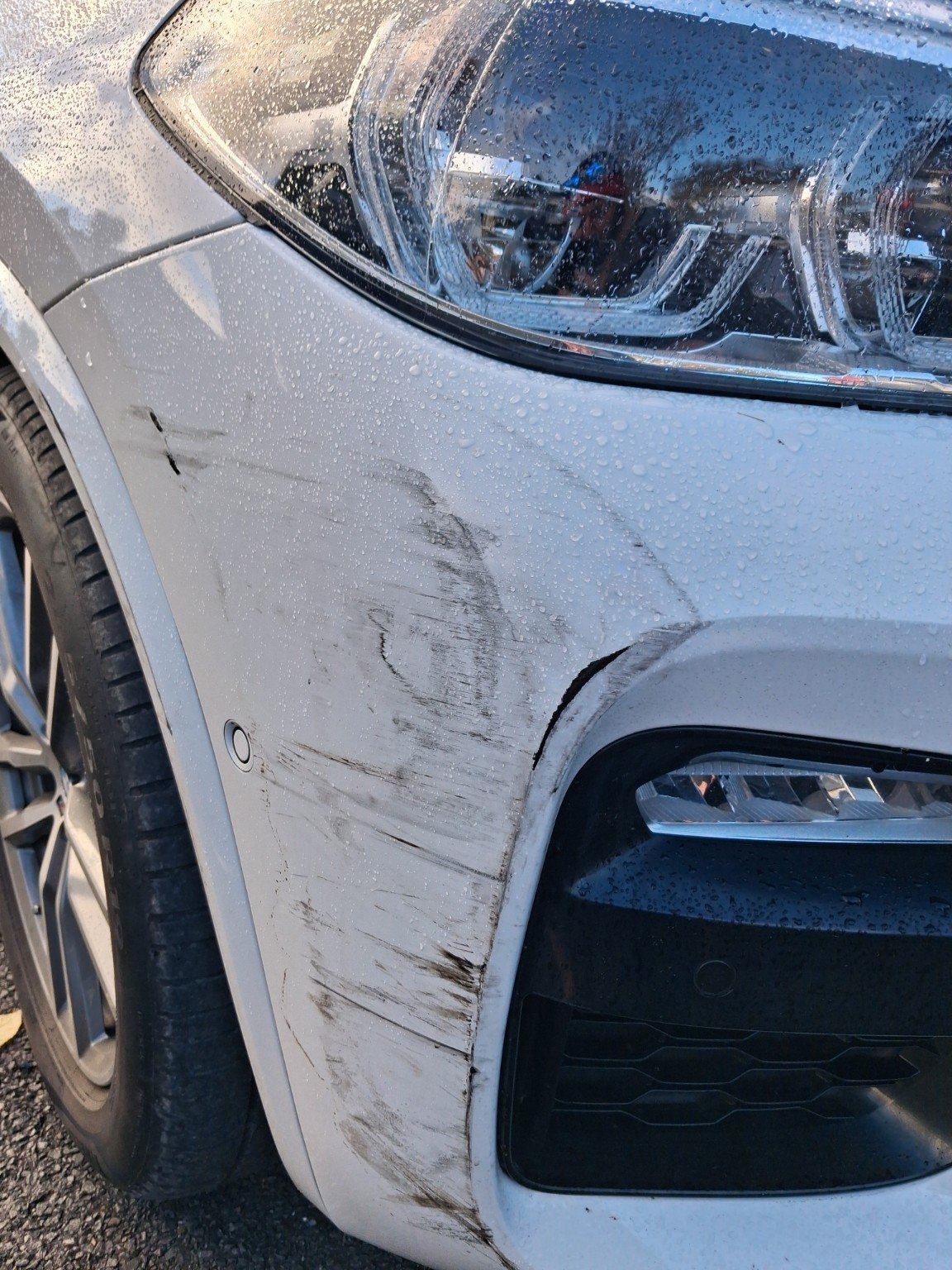 White BMW front guard showing scratches and panel damage before repair